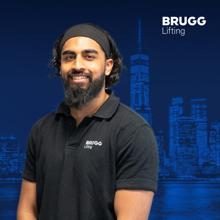 Vithu, Brugg employee, smiling at the camera. He is wearing a black BRUGG polo shirt and standing in front of a blue background."